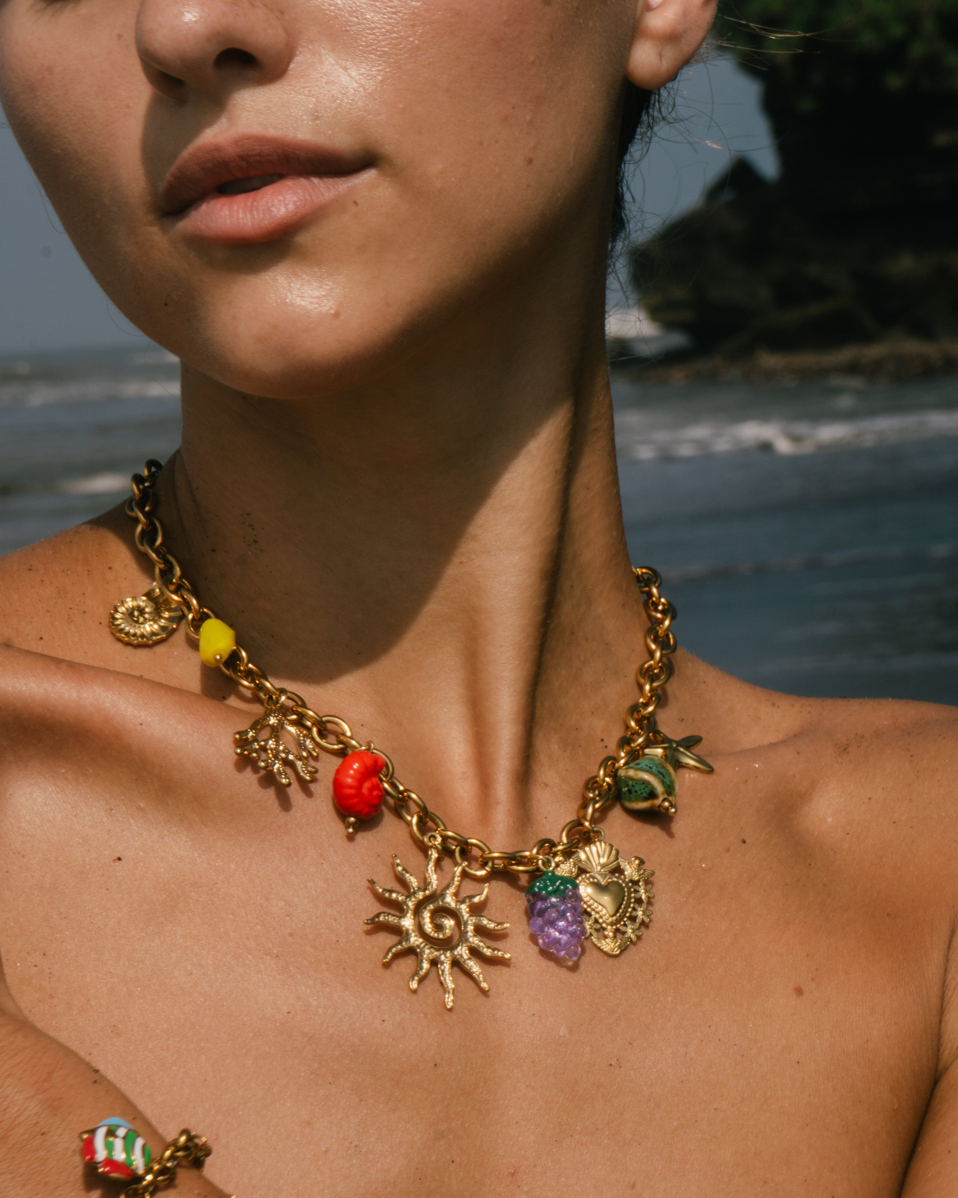 Necklace with colorful charms worn by a person by a body of water