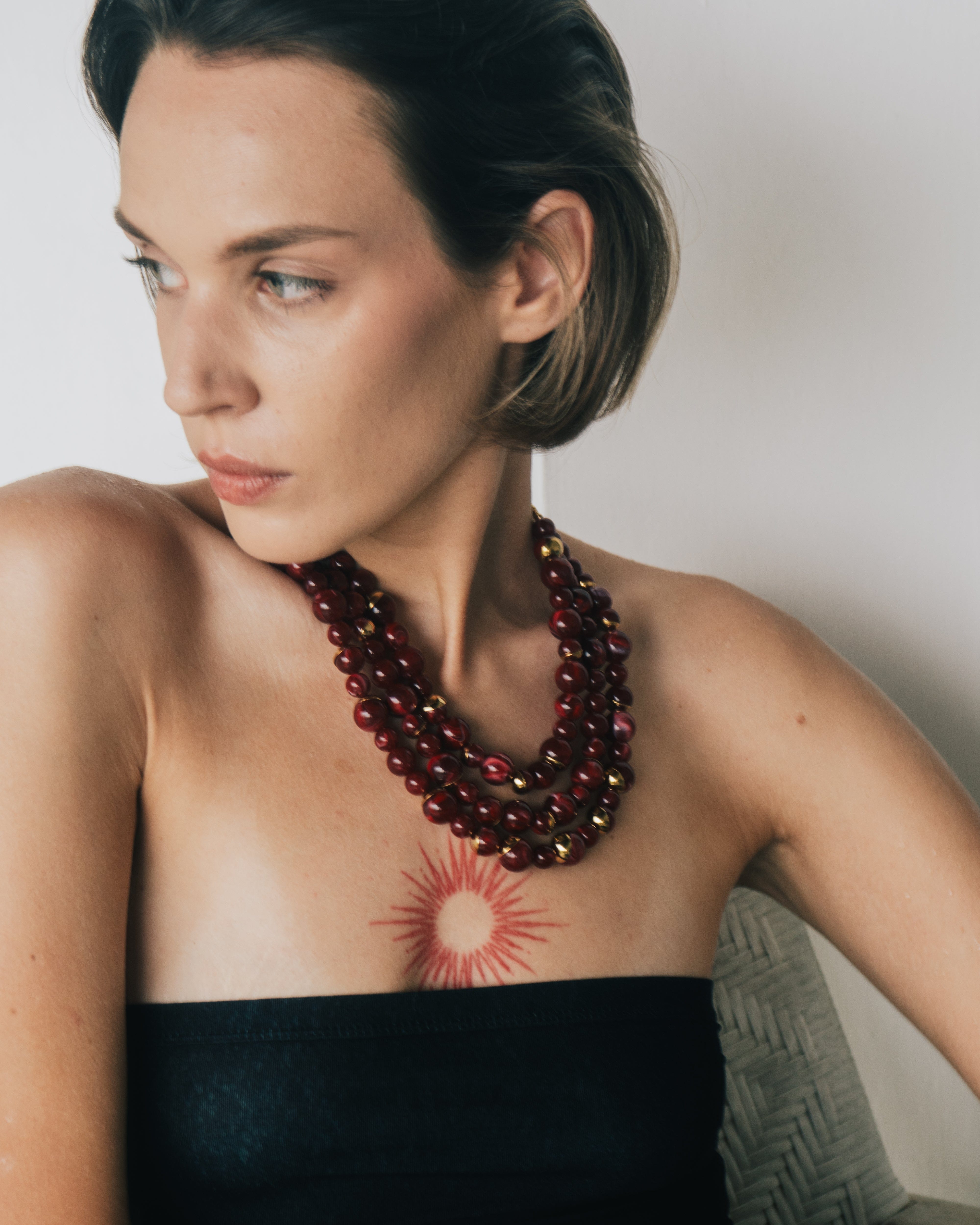 Woman wearing a multicolored beaded necklace against a neutral background