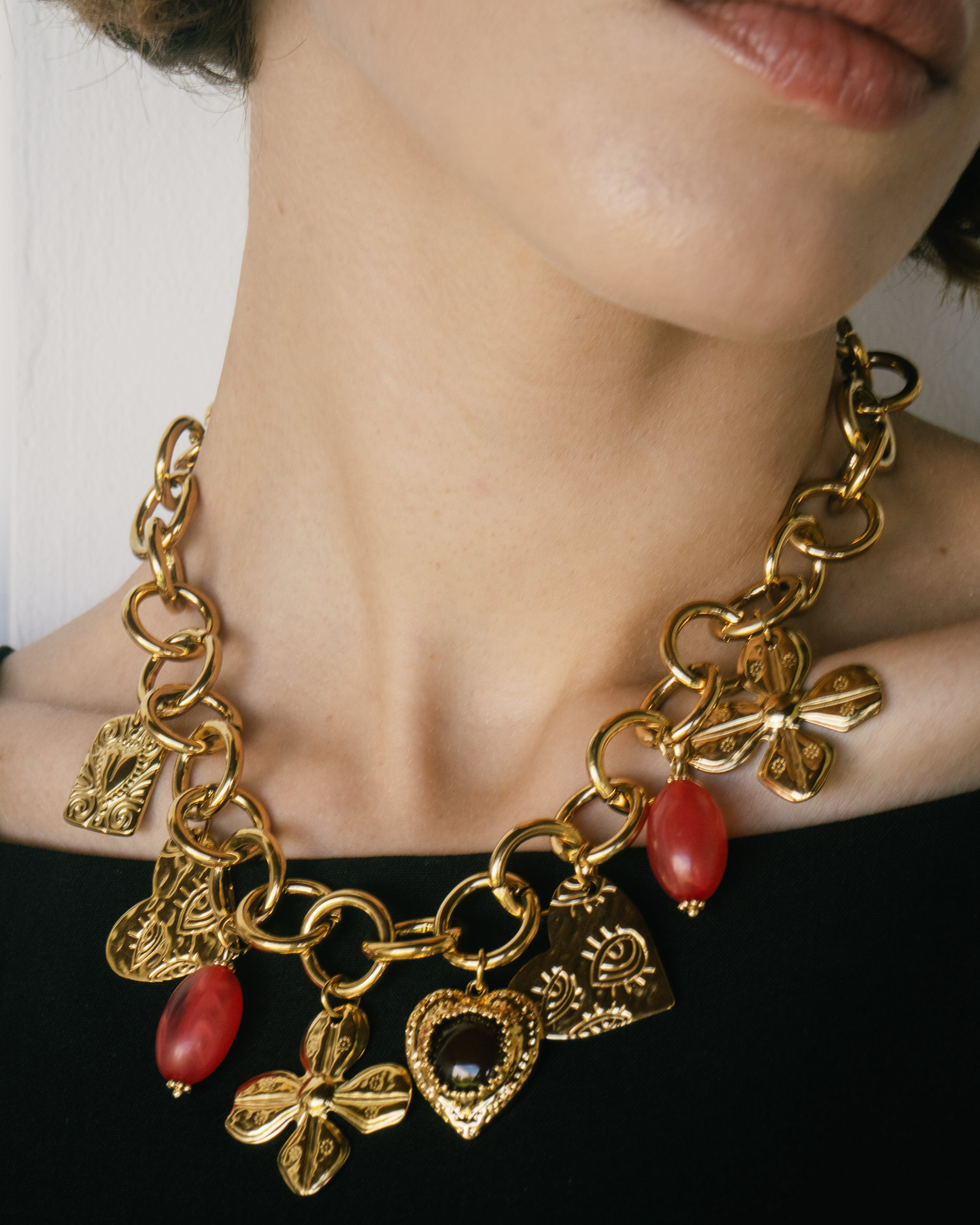 Gold necklace with charms worn by a person against a neutral background